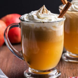 A mug of hot buttered rum garnished with a cinnamon stick