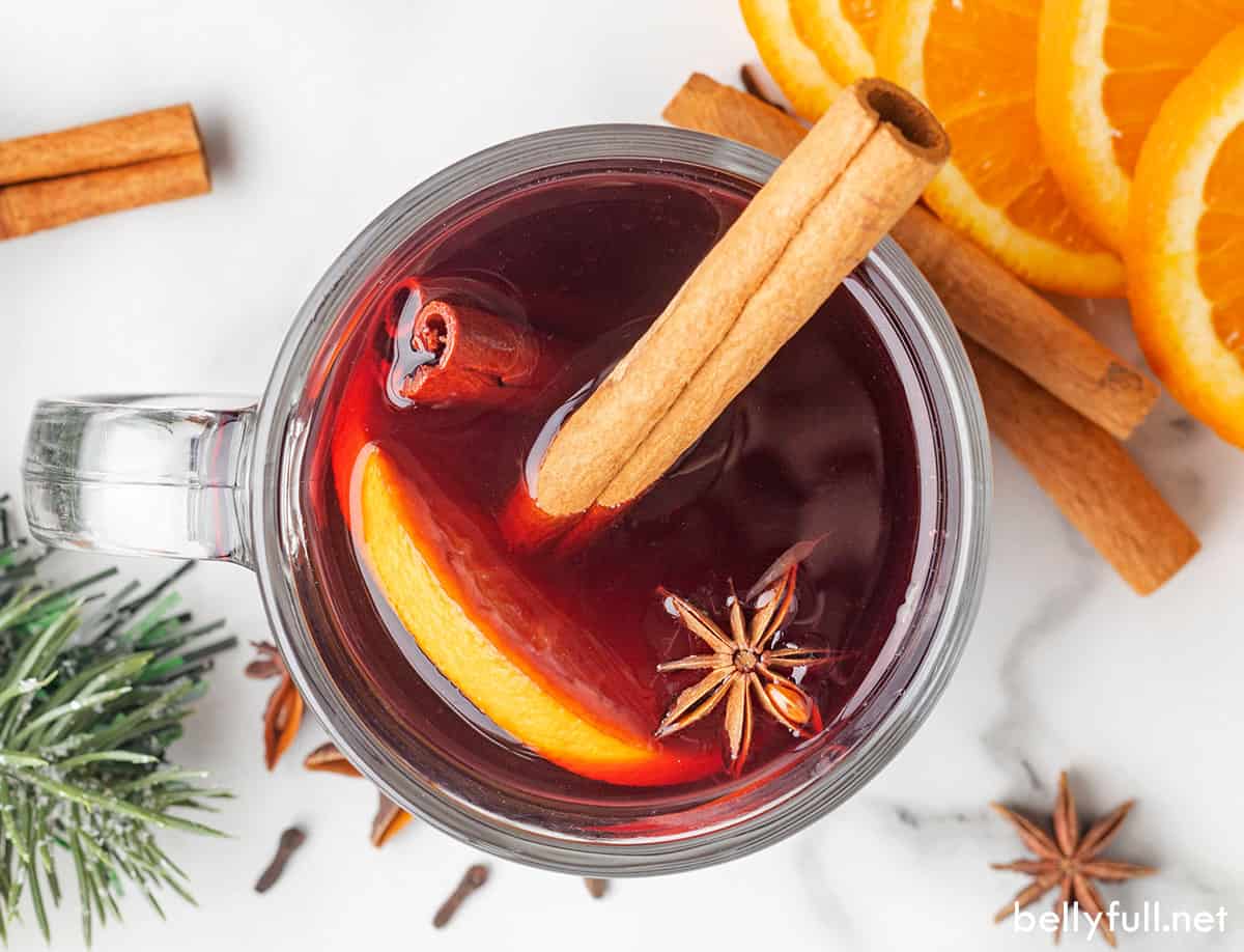 Overhead view of a glass of mulled wine garnished with a cinnamon stick and orange slice