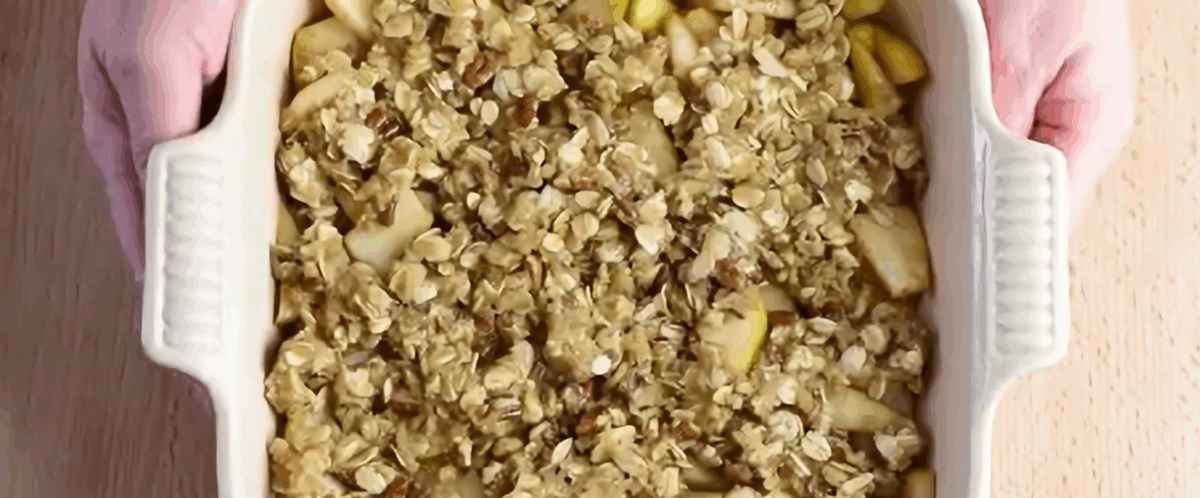 Topping sprinkled over the pears in a white baking dish. 
