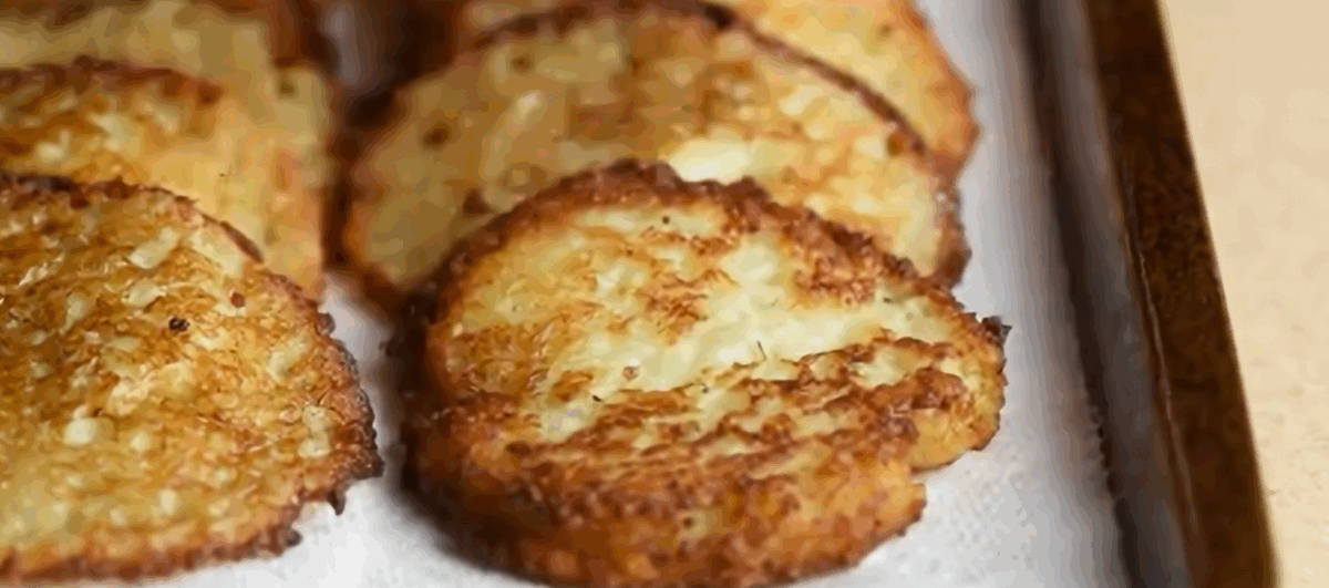 Potato latkes on a paper towel lined baking sheet.