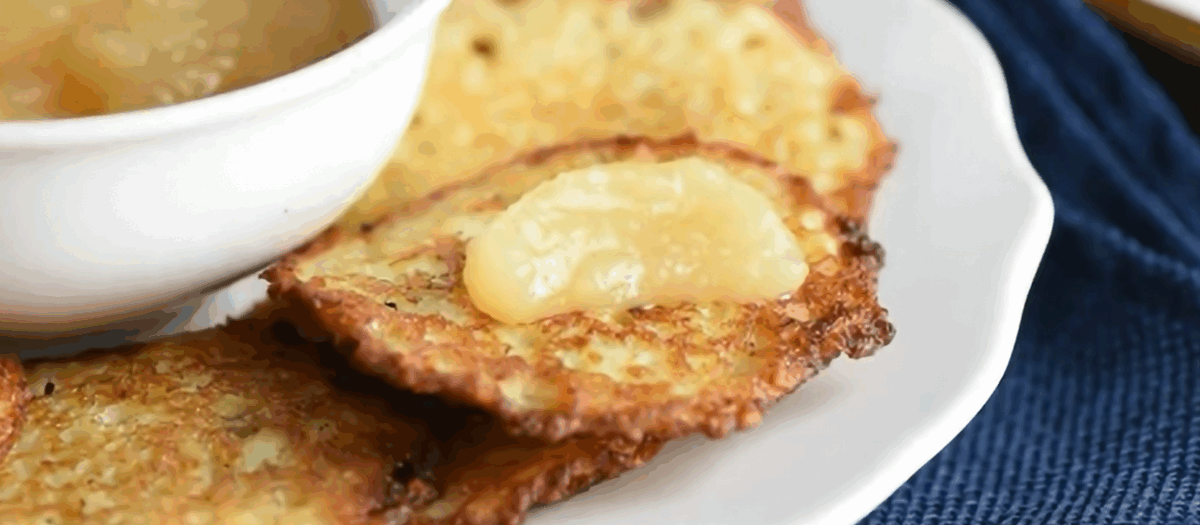 Potato latkes on a white plate with applesauce.