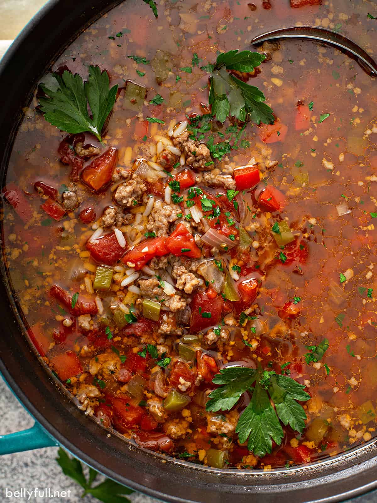 A ladle stirring a big pot of easy stuffed pepper soup