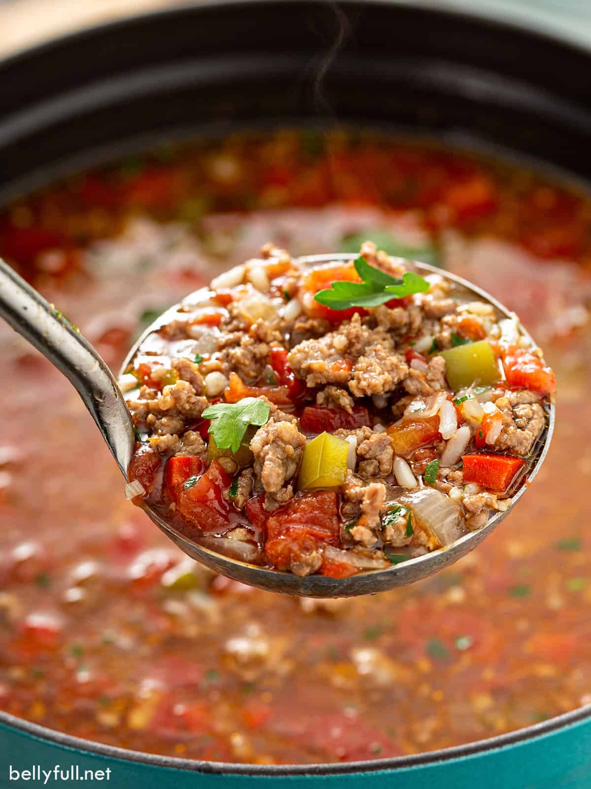 A ladle full of stuffed pepper soup over the pot of soup