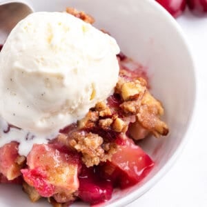 apple cranberry crisp in bowl with scoop of vanilla ice cream