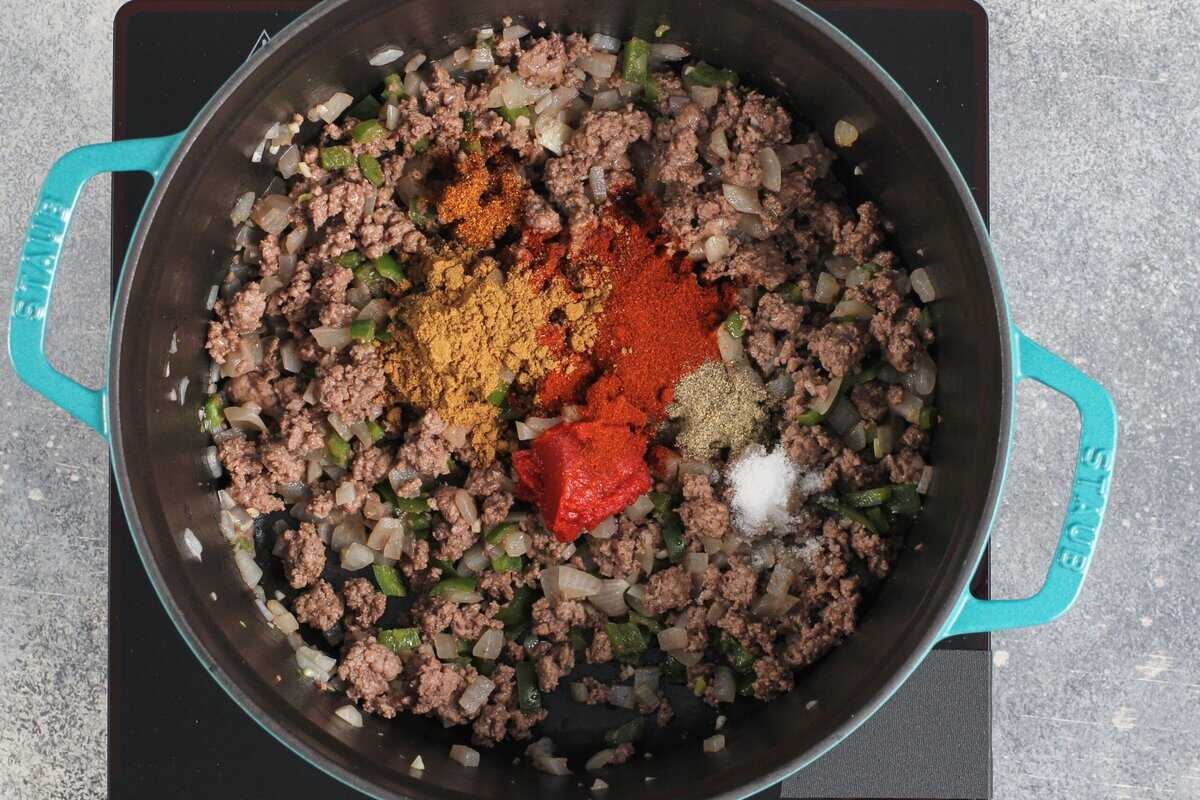 Adding seasonings and spices to the pot with the beef.