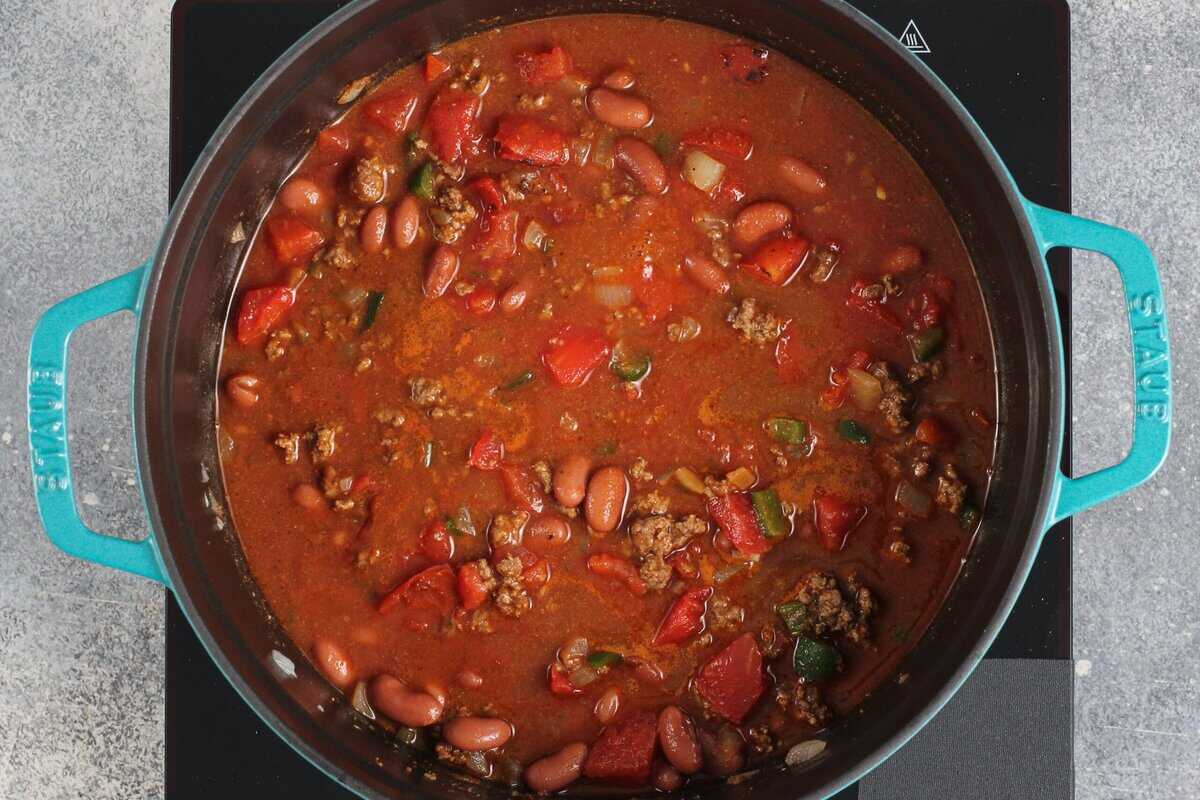Adding broth, tomato sauce, diced tomatoes, and beans to the pot.