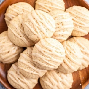 overhead pile of eggnog cookies with icing on wooden plate