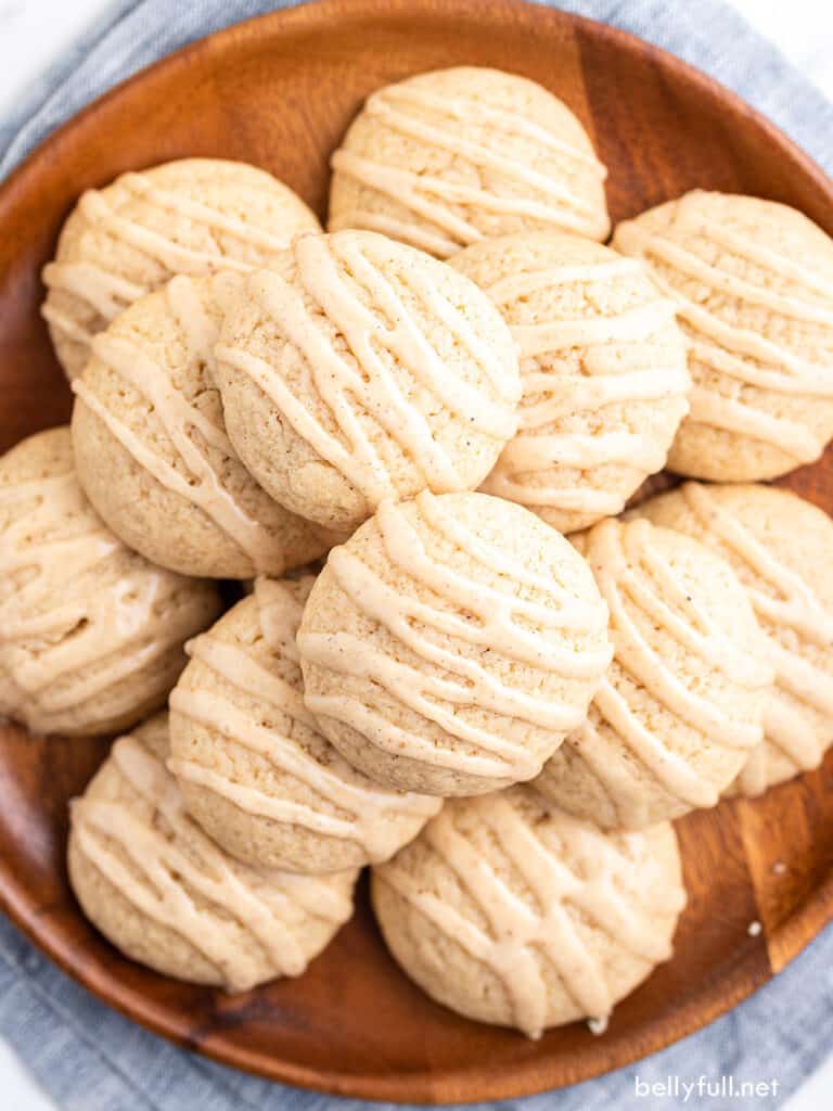 overhead pile of eggnog cookies with icing on wooden plate