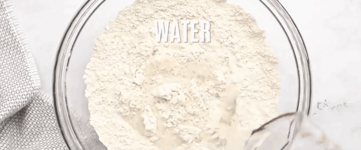 Combining the ingredients to make Dutch oven bread in a glass bowl.