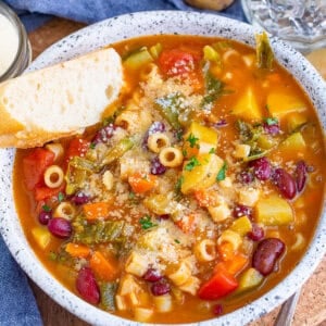 Overhead view of a bowl of minestrone soup with a piece of bread