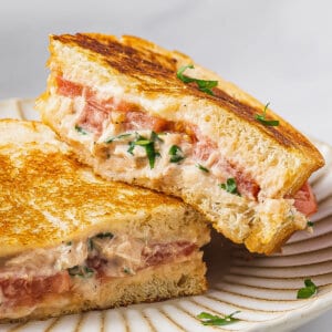 A tuna melt cut in half, one half leaning on the other