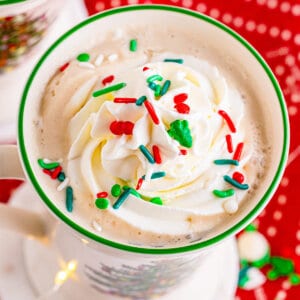 white hot chocolate topped with whipped cream and Christmas sprinkles