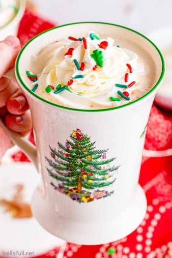 hand holding Christmas mug with white hot chocolate