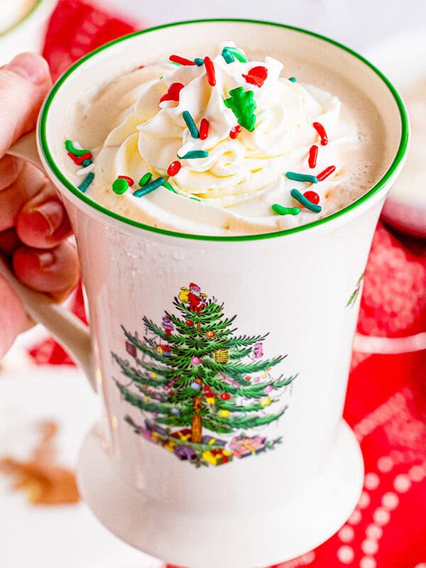 hand holding Christmas mug with white hot chocolate
