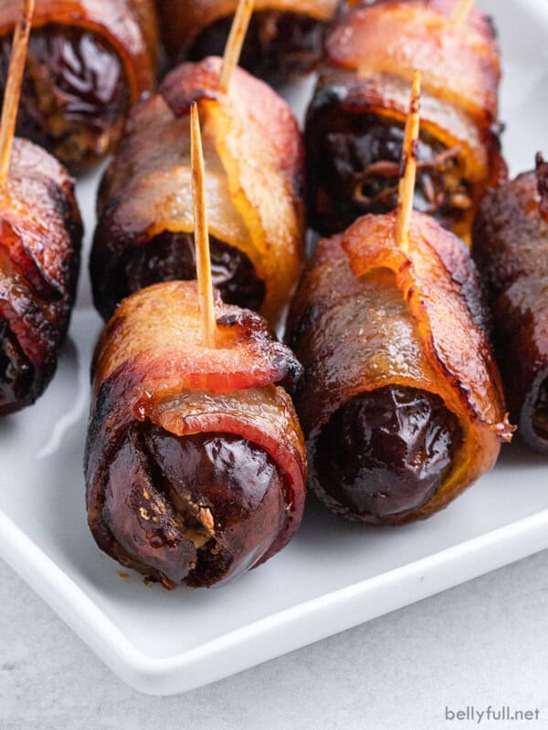 close up bacon wrapped dates with toothpick on white plate
