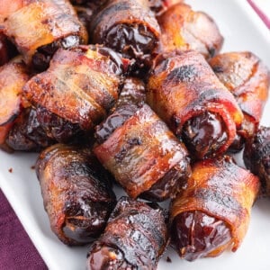 overhead pile of bacon wrapped dates on white serving tray