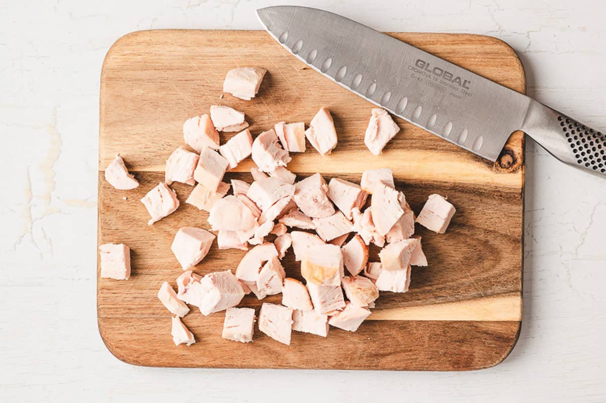 This is the BEST chicken salad recipe. With chicken, cranberries, apples, and pecans, it's wonderful on its own or as a sandwich! Diced chicken on a cutting board