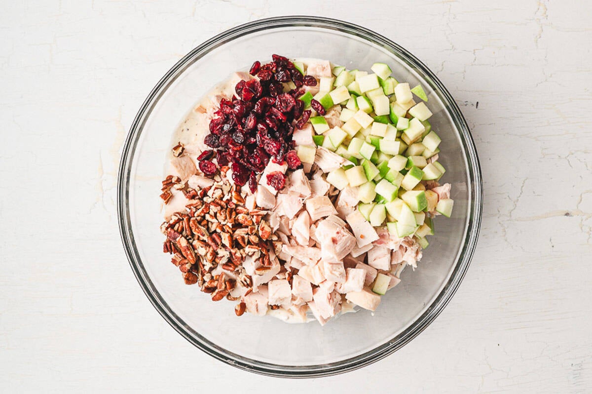 This is the BEST chicken salad recipe. With chicken, cranberries, apples, and pecans, it's wonderful on its own or as a sandwich! Chicken, cranberries, apples, and pecans in a bowl