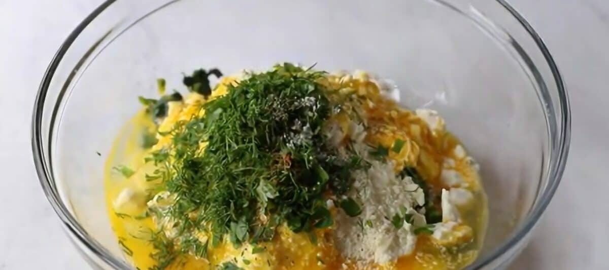 Spanakopita filling ingredients in a glass bowl. 