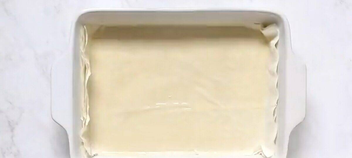 Layers of phyllo dough in a white baking dish.