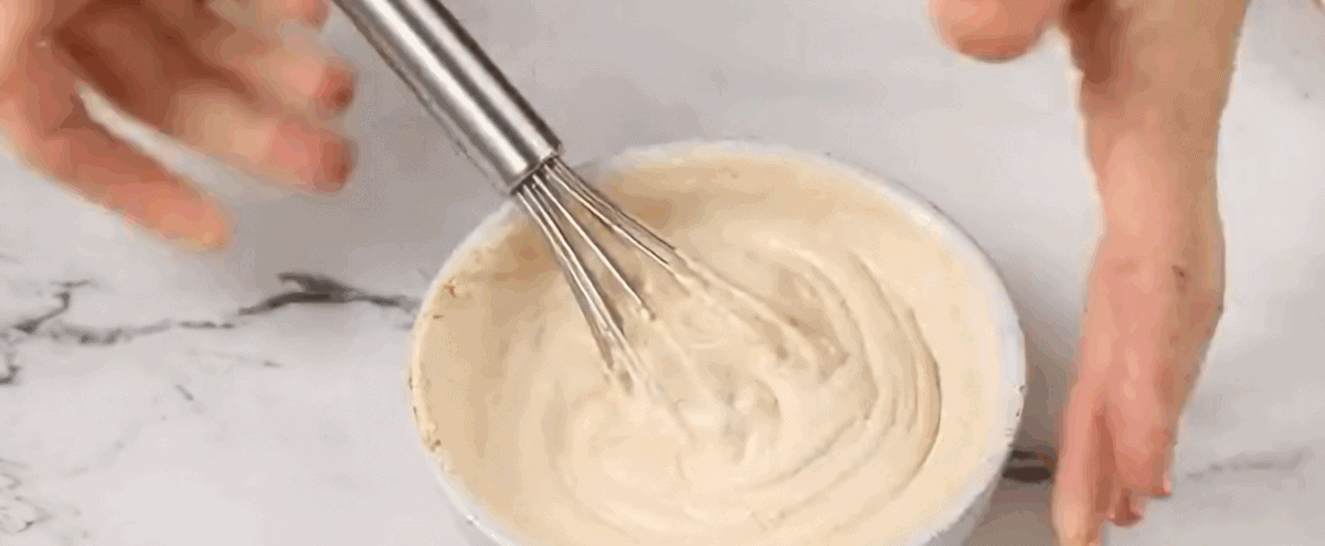 The sour cream layer in a bowl with a whisk.