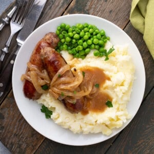 overhead picture of bangers and mash with onion gravy on wooden board