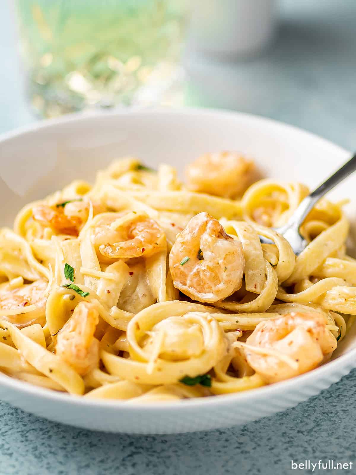 creamy pasta with shrimp on fork in white bowl