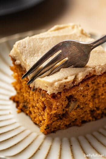 fork slicing into a piece of frosted tomato soup cake