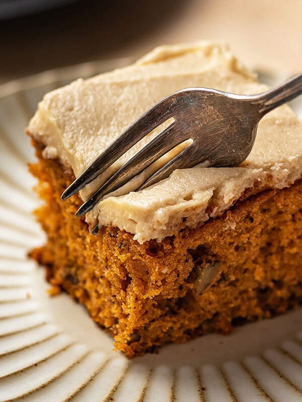 fork slicing into a piece of frosted tomato soup cake