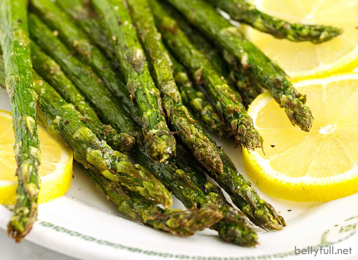 Close-up of air fryer asparagus on a plate with lemon slices