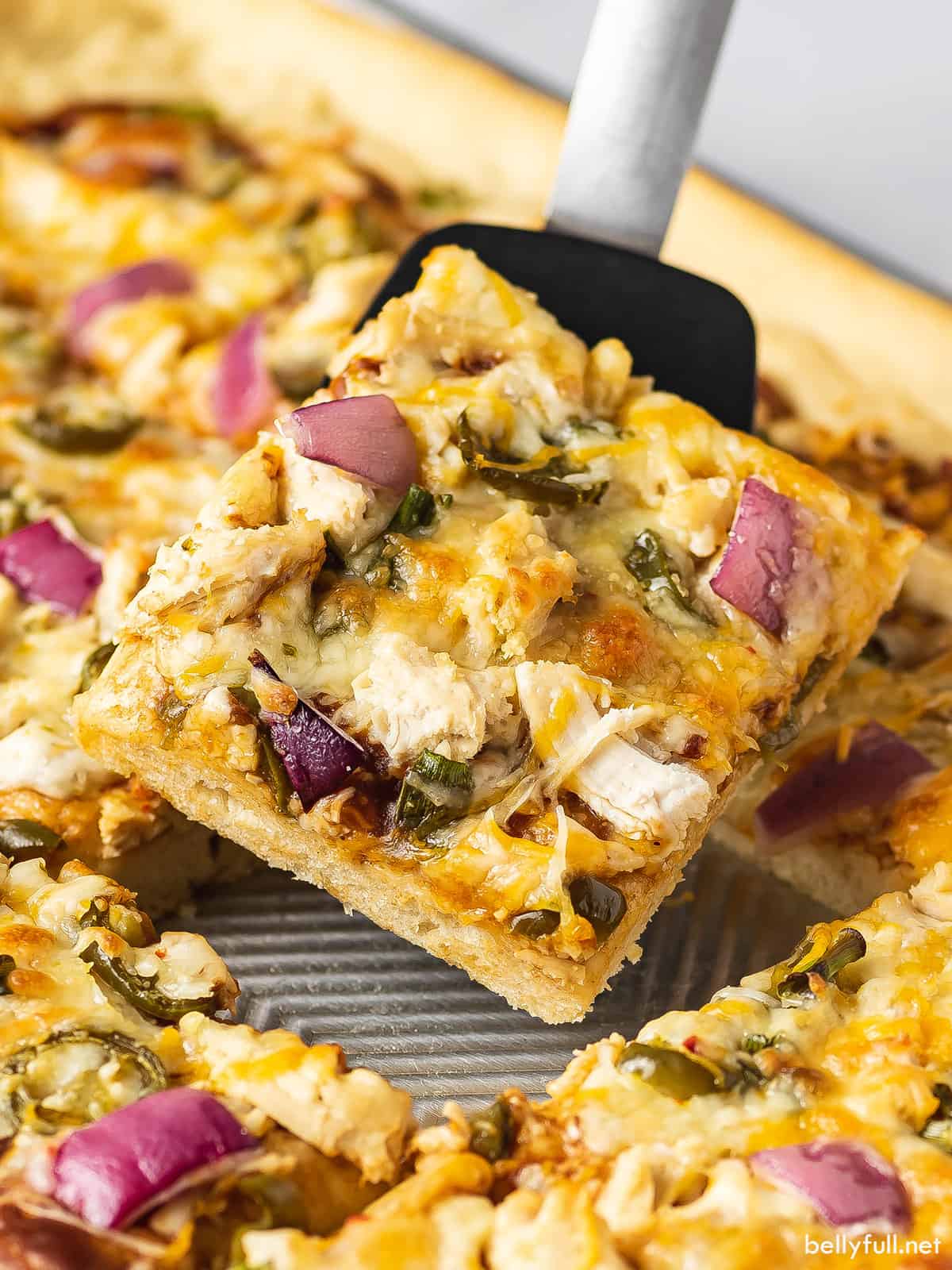 A slice of BBQ chicken pizza being served