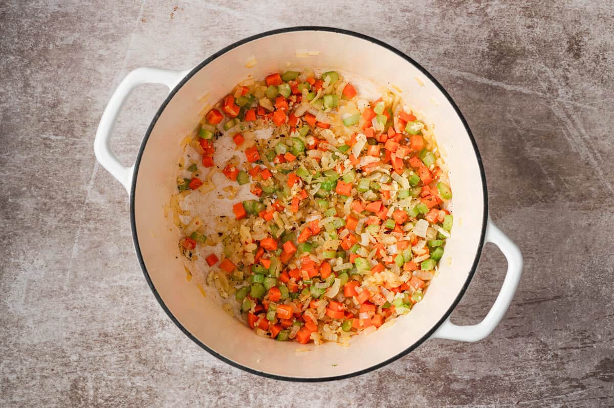 Diced onion, carrot, and celery sautรฉing in a Dutch oven to build the soup base