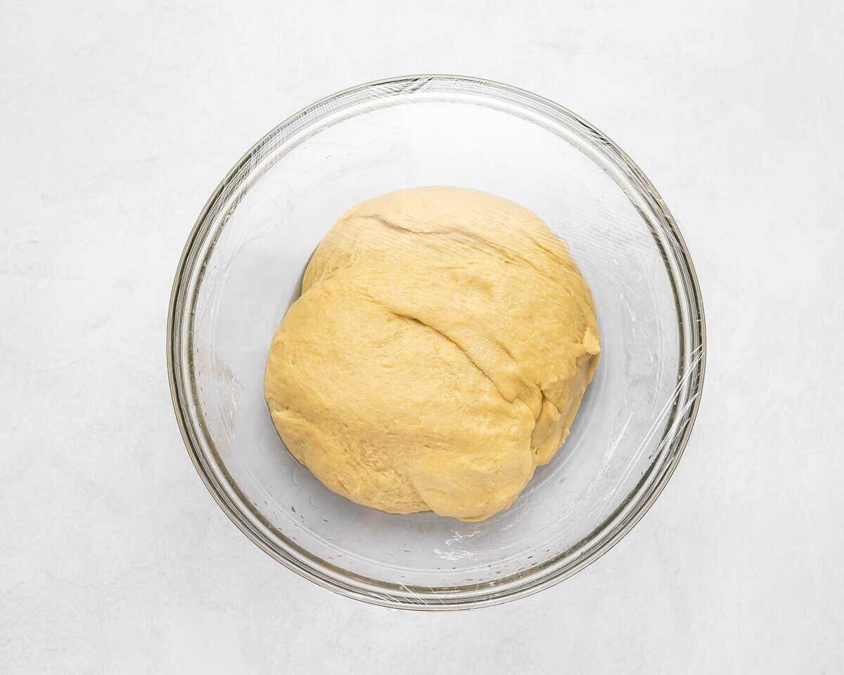 Formed dough in a bowl covered with plastic wrap.