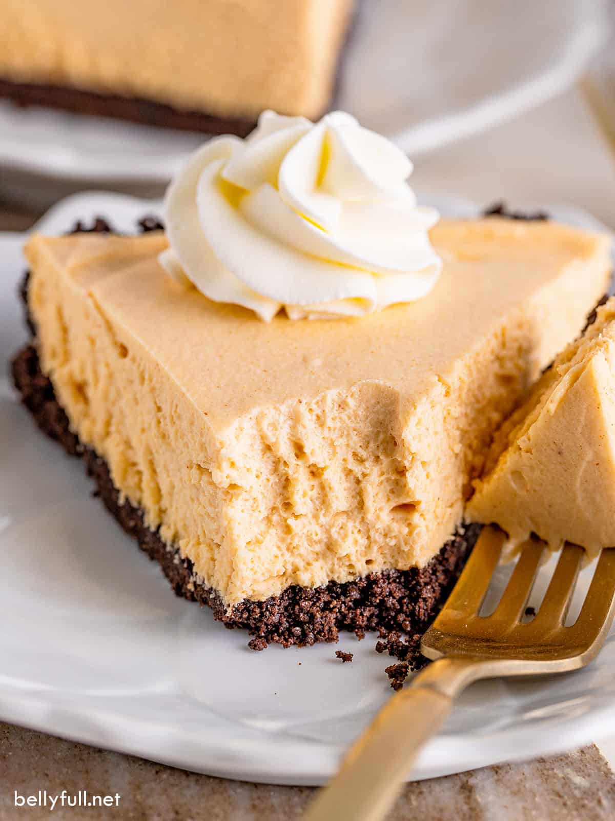 A slice of peanut butter pie with a bite on a fork next to the slice