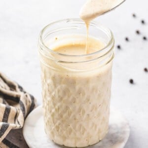 A glass jar with a spoon of Alabama white sauce above it