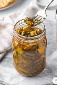 A fork with a candied jalapeno over a jar of cowboy candy