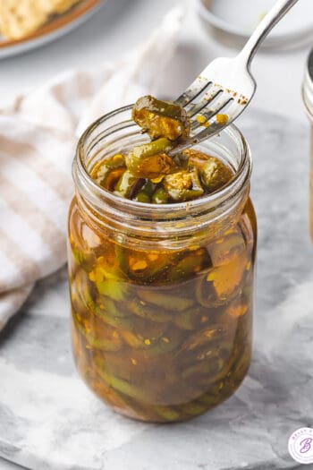 A fork with a candied jalapeno over a jar of cowboy candy