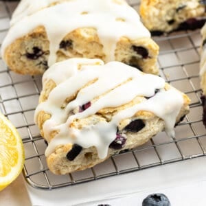 close up glazed lemon blueberry scone on cooling rack