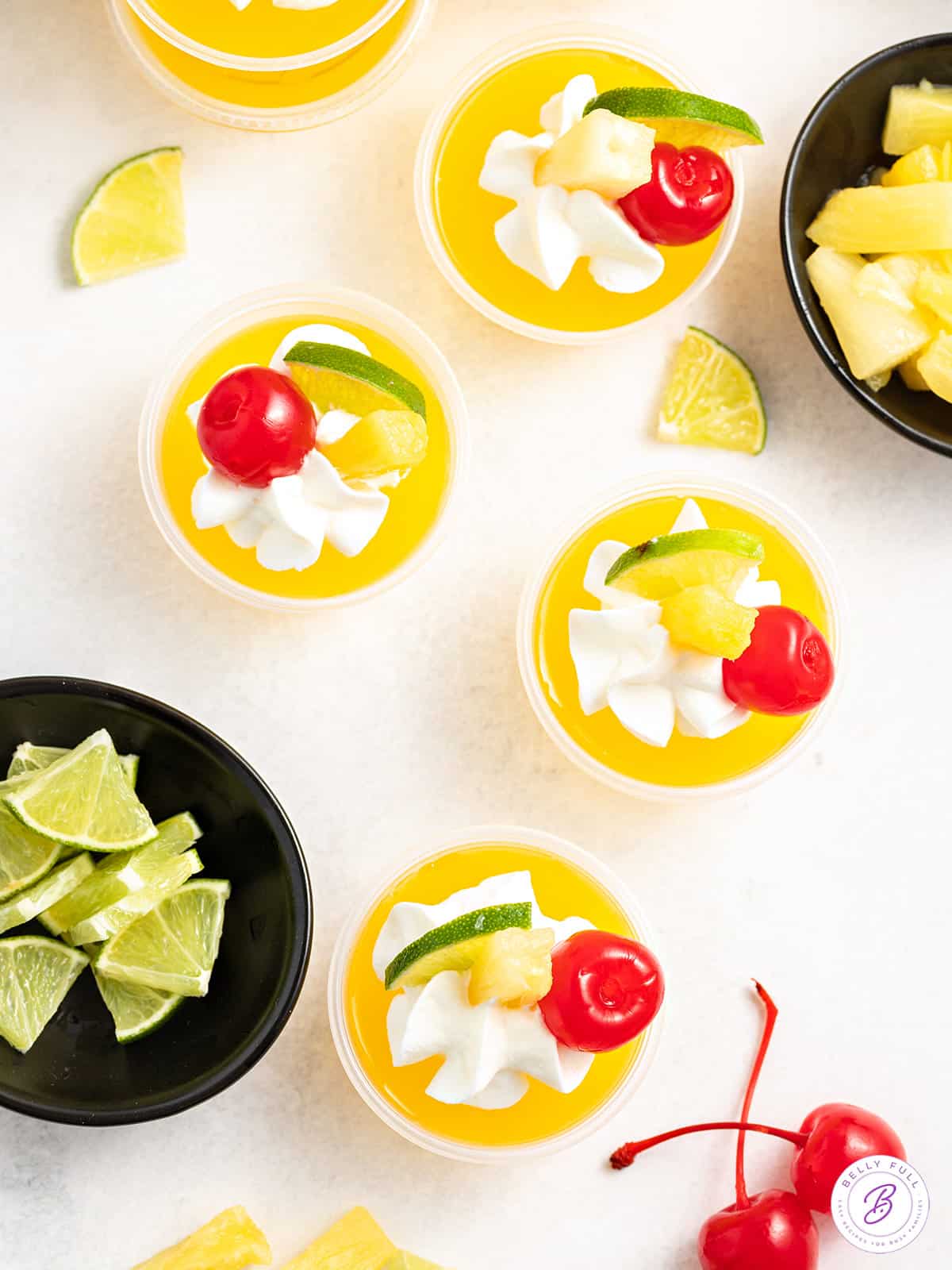 yellow jello shots garnished with whipped cream, lime wedge, and maraschino cherry