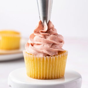 strawberry buttercream frosting being piped onto cupcake