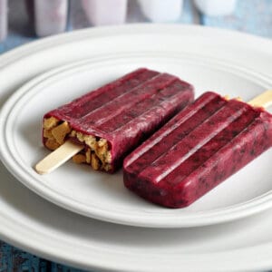 2 blackberry popsicles on a white plate