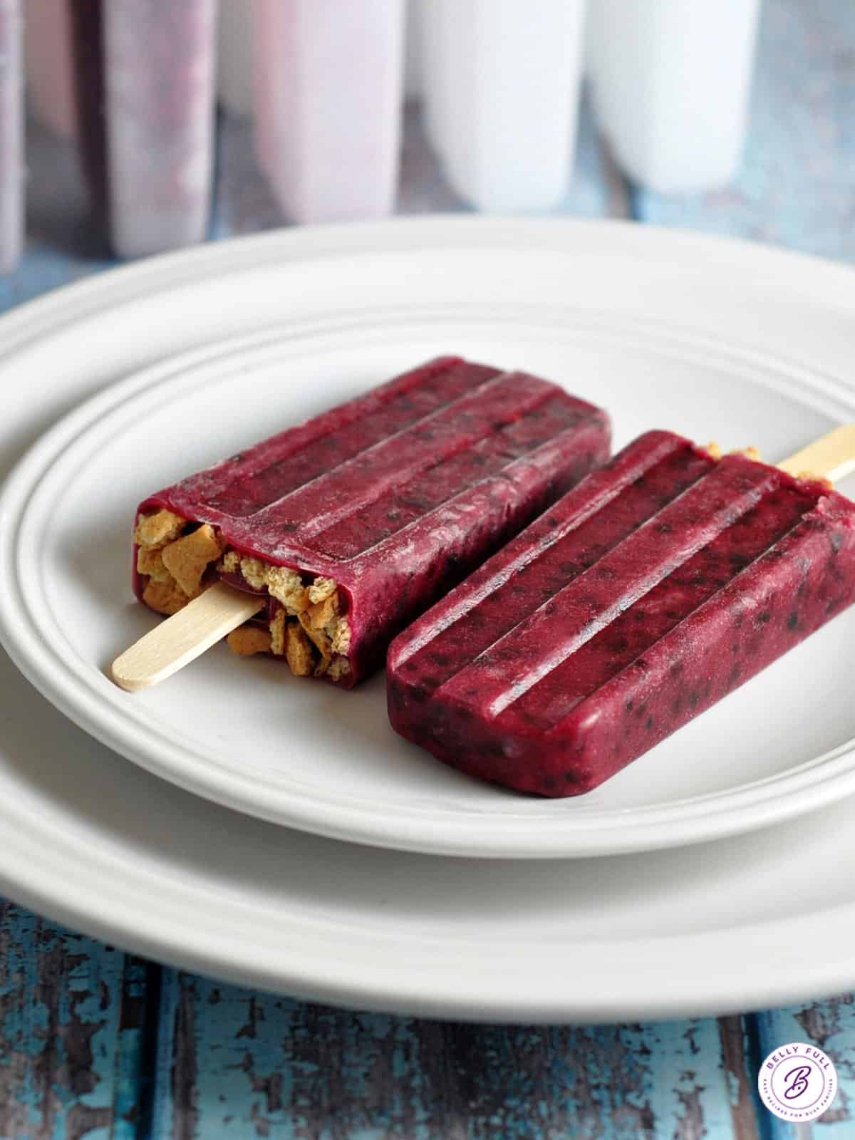 2 blackberry popsicles on a white plate