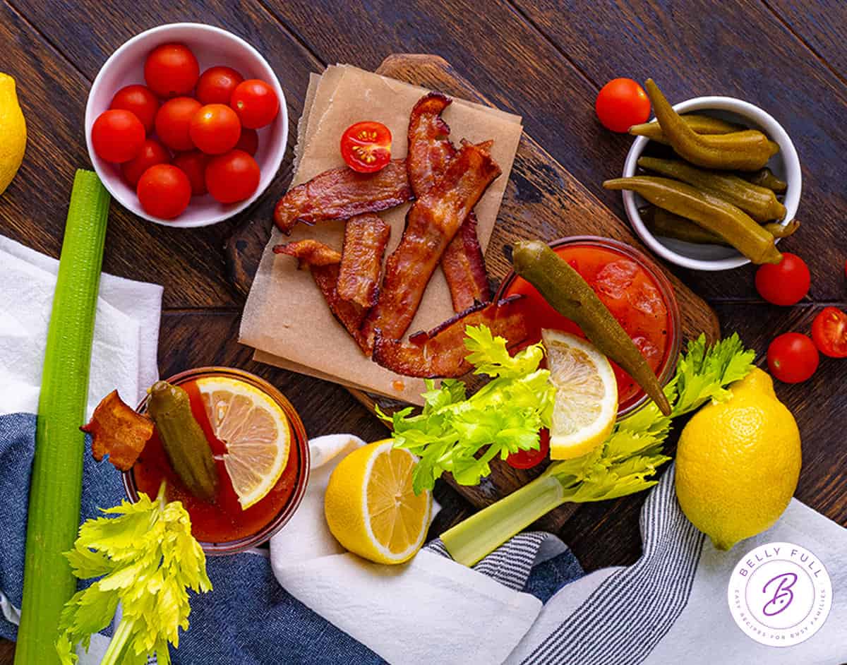 Cherry tomatoes, bacon, celery, lemon, and other Bloody Mary garnishes on the table