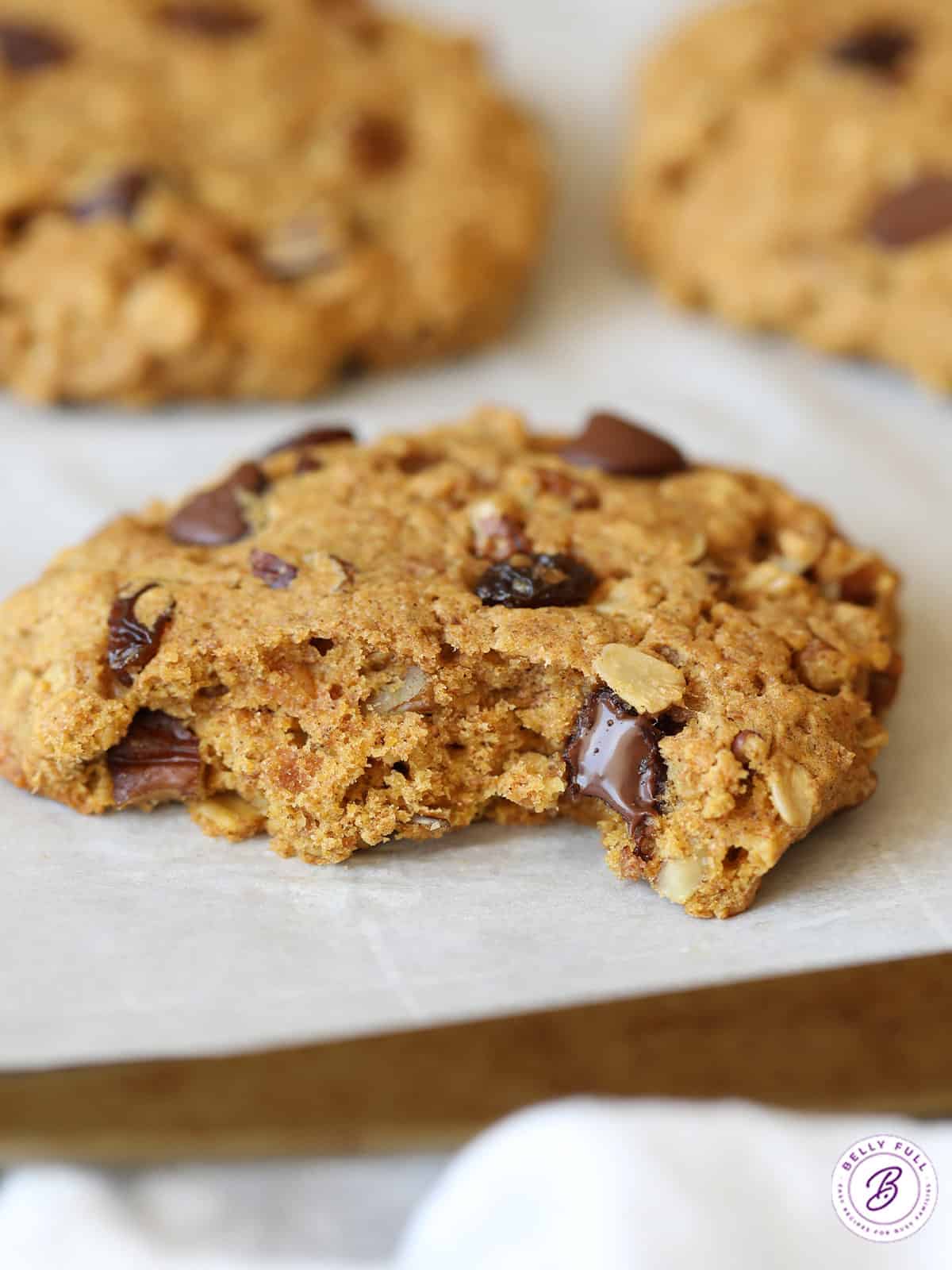 close up large cookie with bite taken on baking sheet