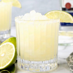 Side view of a frozen margarita in a glass garnished with a lime slice