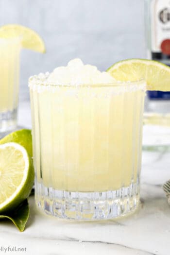 Side view of a frozen margarita in a glass garnished with a lime slice