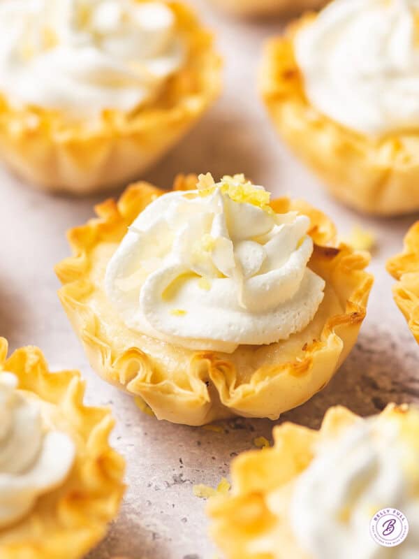 close up mini lemon tart with whipped cream and lemon zest