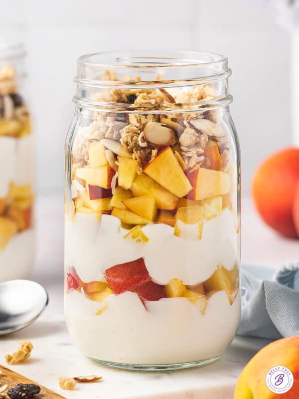 glass jar of yogurt peach parfait