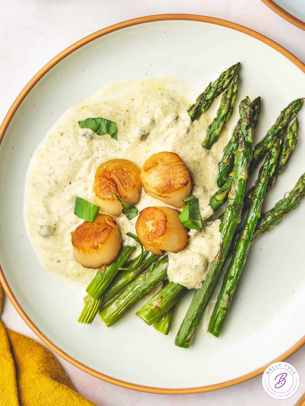 Overhead view of a plate of scallops with pesto cream