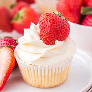 A frosted strawberry shortcake cupcake on a white plate